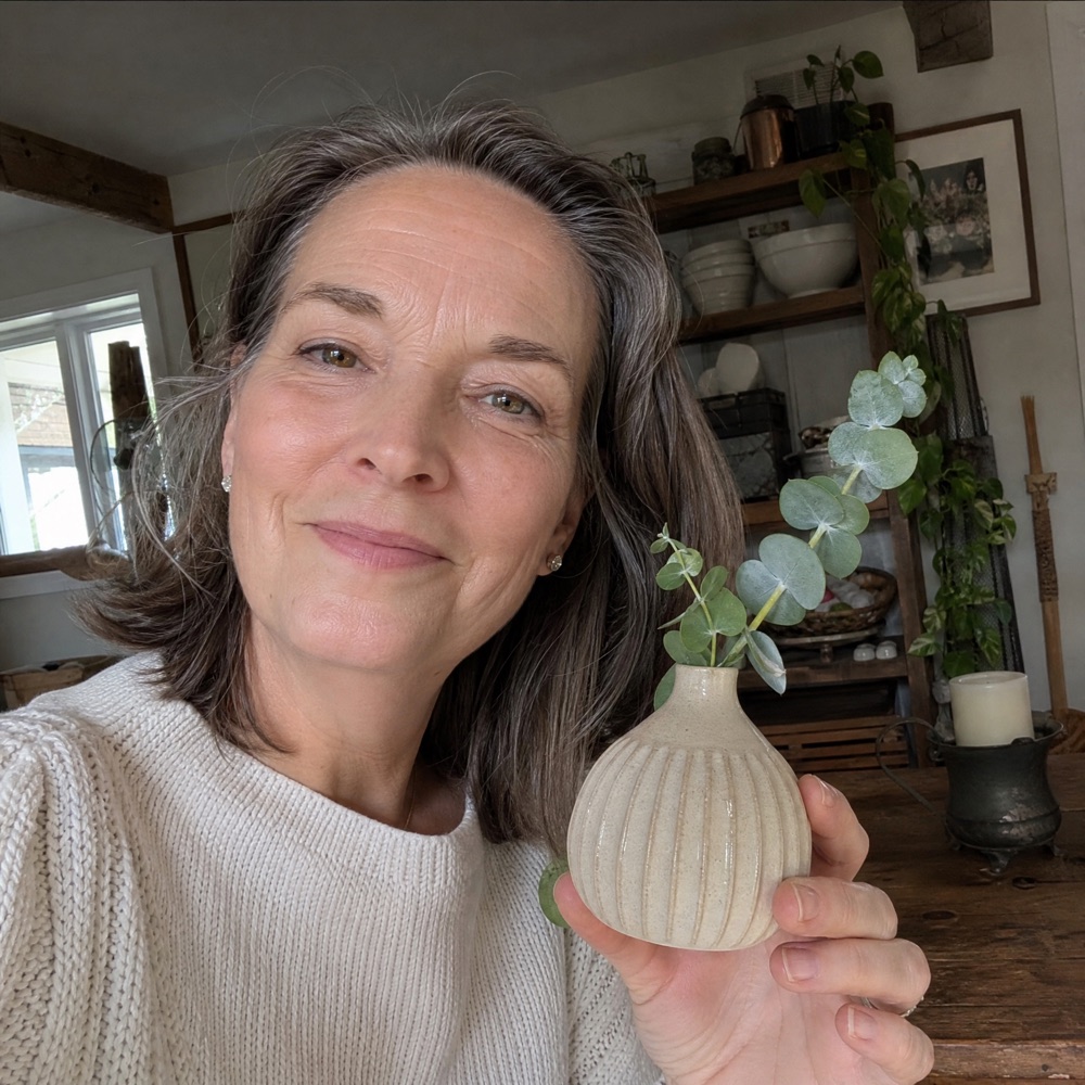 Angela T. holding her handmade ceramic piece at home