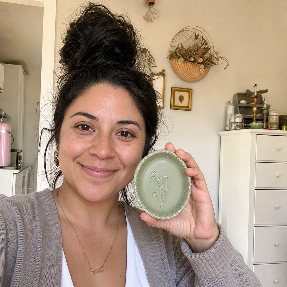 Claudia F. holding her handmade ceramic piece at home