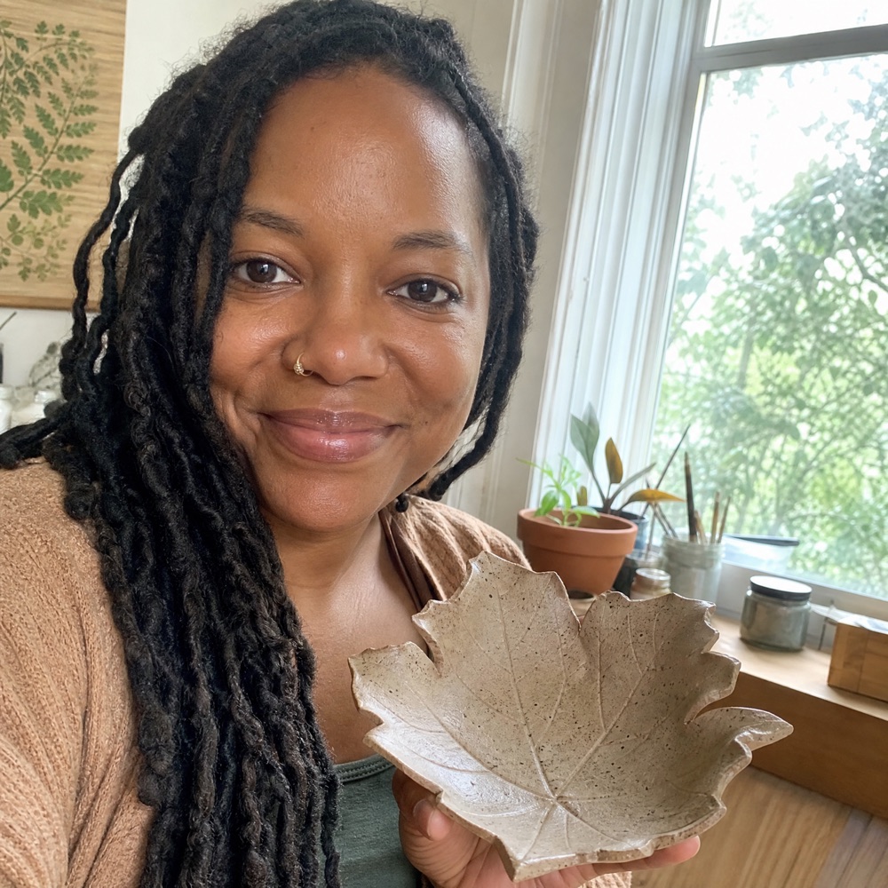 Renata P. holding her handmade ceramic piece at home